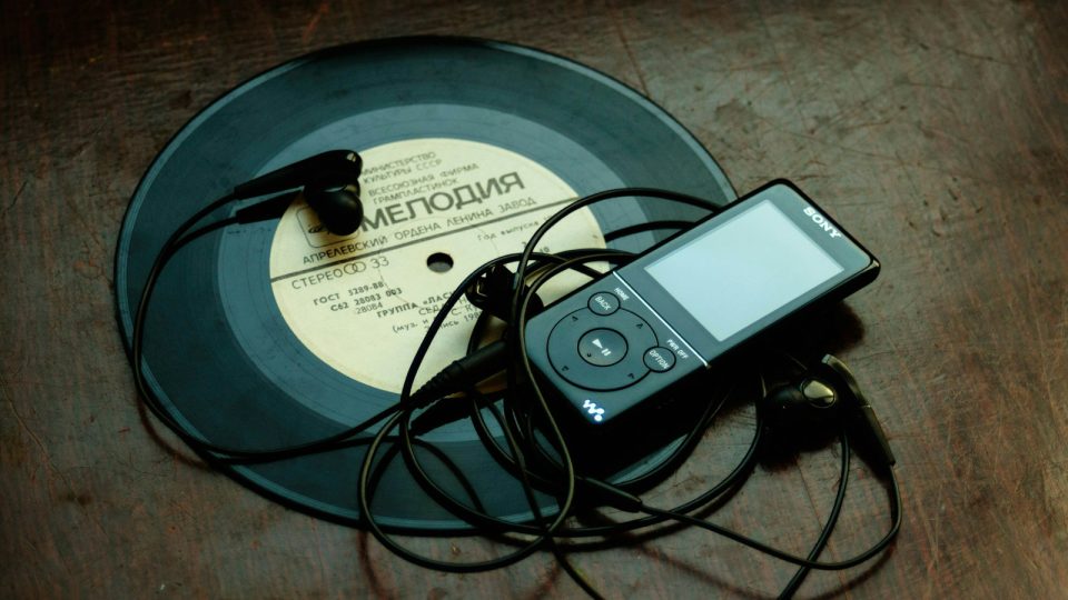 in-ear headphones plugged in black Sony Walkman on vinyl record